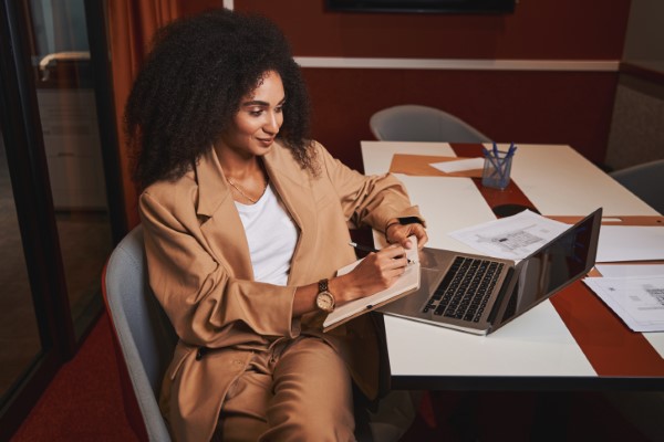 Imagen de una mujer haciendo diversas notas para su interpretación consecutiva, mientras está en una reunión a través de una plataforma digital.